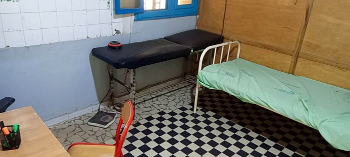 L'infirmerie : table d'examen et lit de repos, sol carrelé en damier