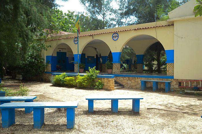 Le préau à arcades du Groupe Scolaire Educazur et ses bancs bleus, vus depuis la cour